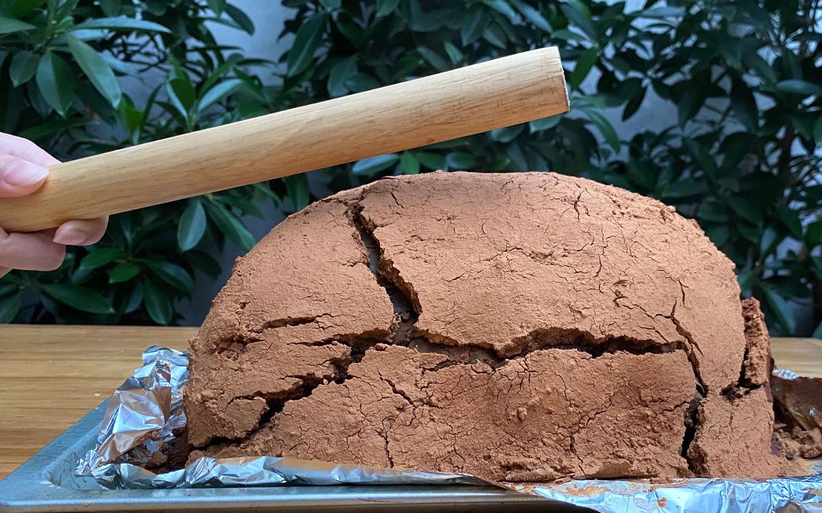 Beggar's Chicken — the baked clay shell cracked open with a wooden mallet on a baking tray