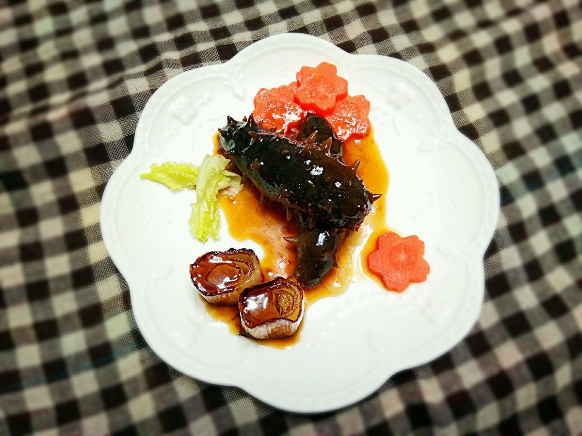 Braised Sea Cucumber — a whole sea cucumber glazed dark with soy and scallion oil, garnished and plated for a banquet