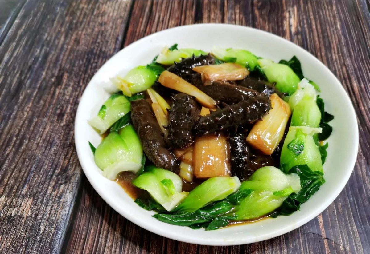 Braised Sea Cucumber close-up — the sea cucumber under a clinging brown sauce with thick braised scallion segments