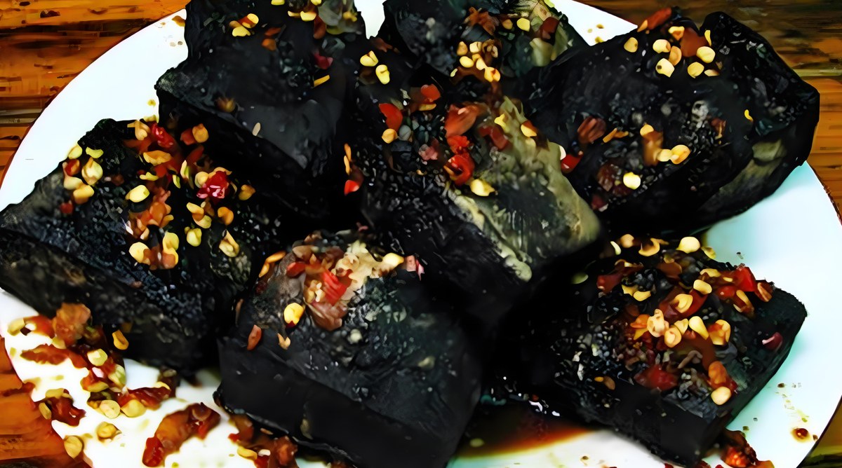 Changsha stinky tofu close-up — the blistered black crust and the chilli-garlic dressing