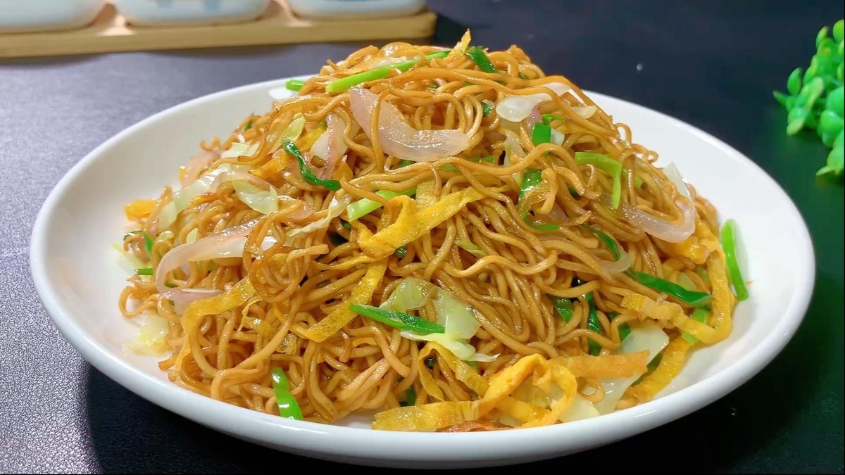 Chow Mein — a heaped plate of egg noodles turned dark with soy, cabbage and scallion through it