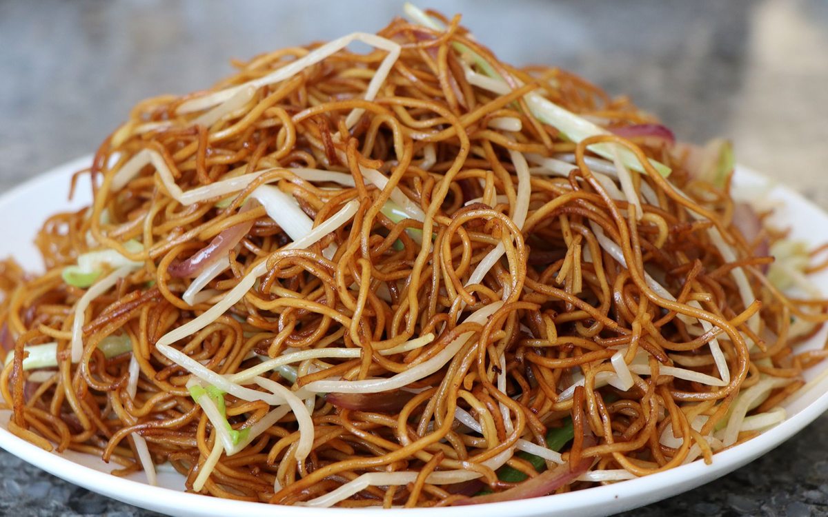 Chow Mein close-up — noodles glossy with dark soy, bean sprouts and onion for crunch