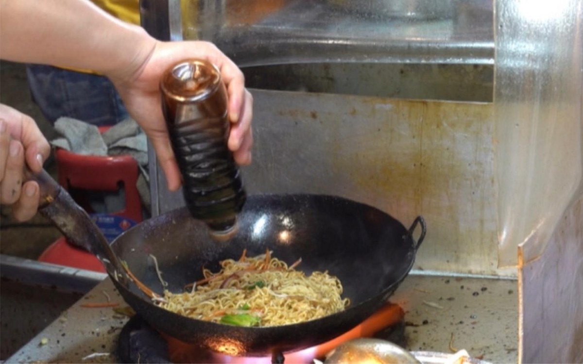Chow Mein in the wok — noodles over open flame as the soy goes in, which is where the wok hei comes from