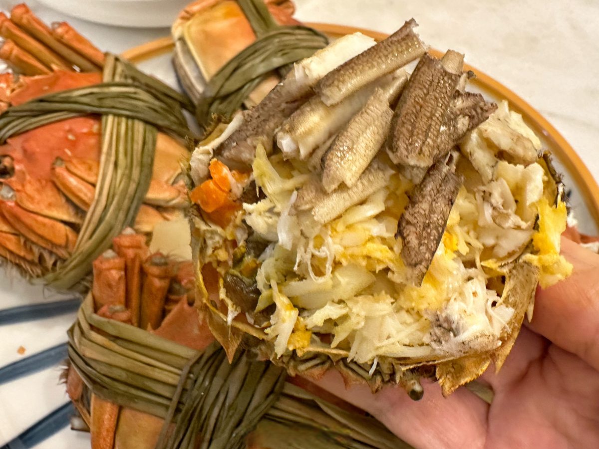 Crab Roe Soup Dumpling — hand-picked crab meat and roe in the shell, with whole steamed hairy crabs behind it