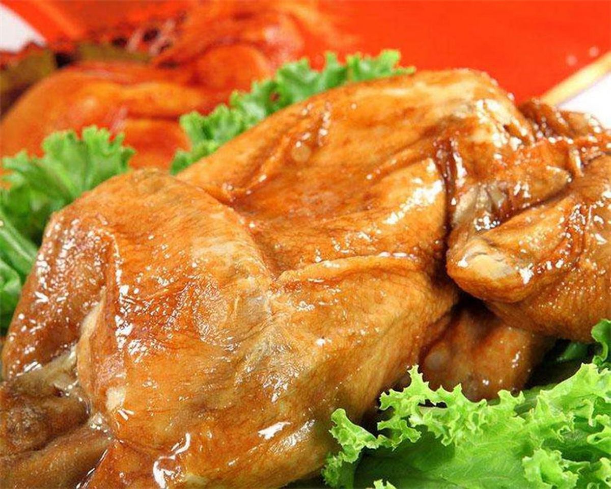 Dezhou braised chicken — a whole amber-glazed five-spice braised chicken, glossy with its braising liquid, on a serving platter