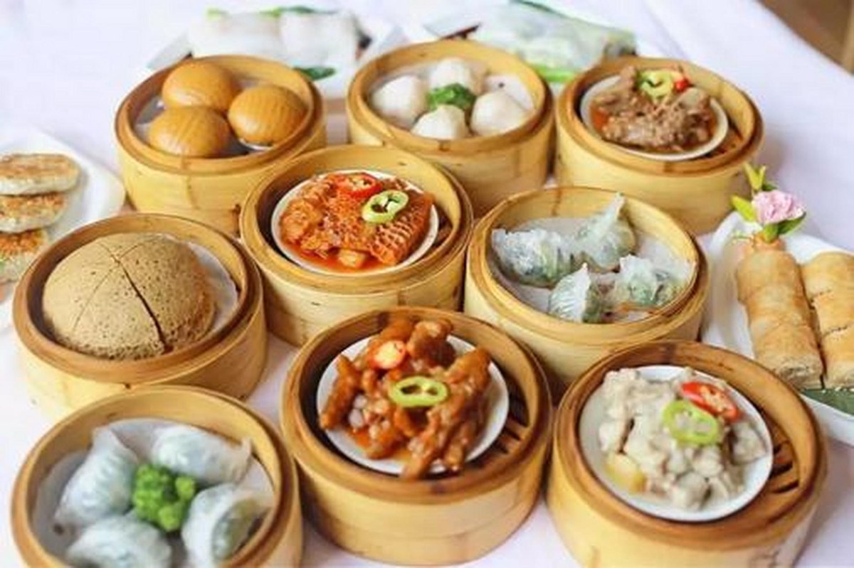A yum cha table spread — steamers, plates and bowls crowded together, and nobody in a hurry