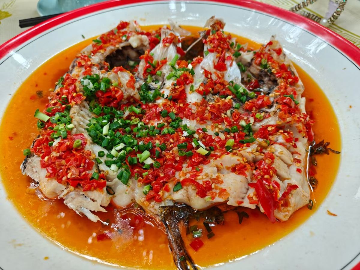 Duo Jiao Fish Head served at the table on its plate, chopsticks alongside