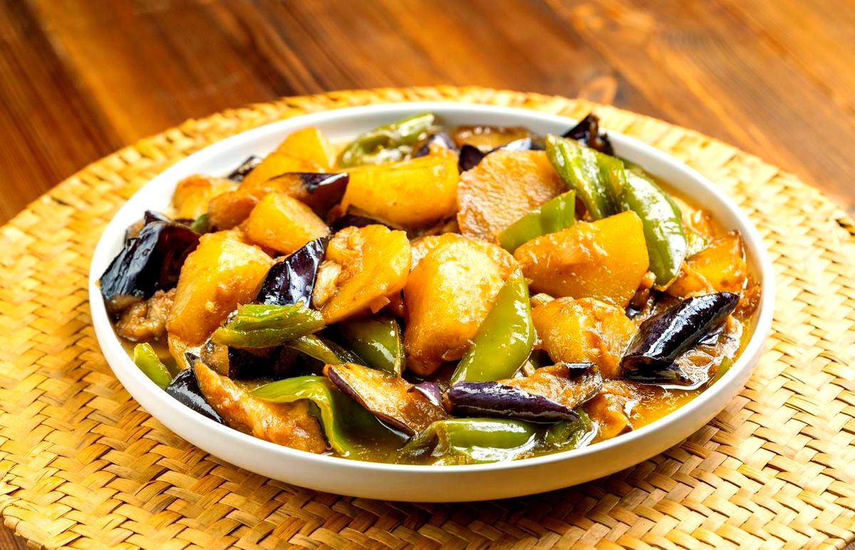 Earth's Three Fresh — a white plate of glossy braised eggplant, potato and green pepper on a rattan mat