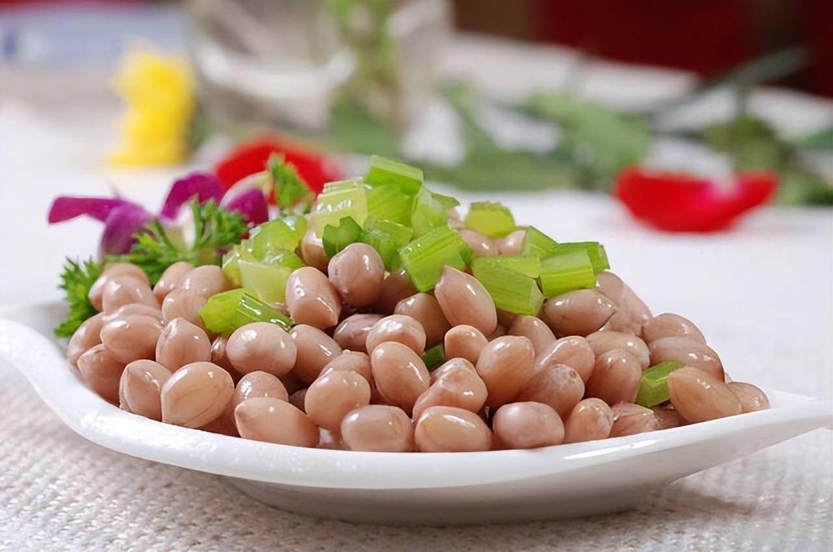 A plate of boiled peanuts with chopped celery, the classic cold dish set out with a glass of baijiu