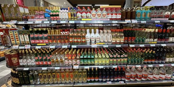 Rows of baijiu bottles with price tags on a liquor-store shelf