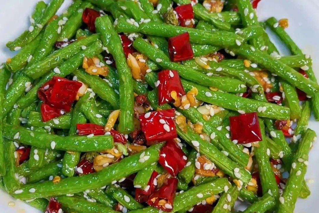 Gan Bian Si Ji Dou over rice — the finished dish on a simple white plate, beans tangled with pork and chilies, steam rising, a bowl of rice beside it