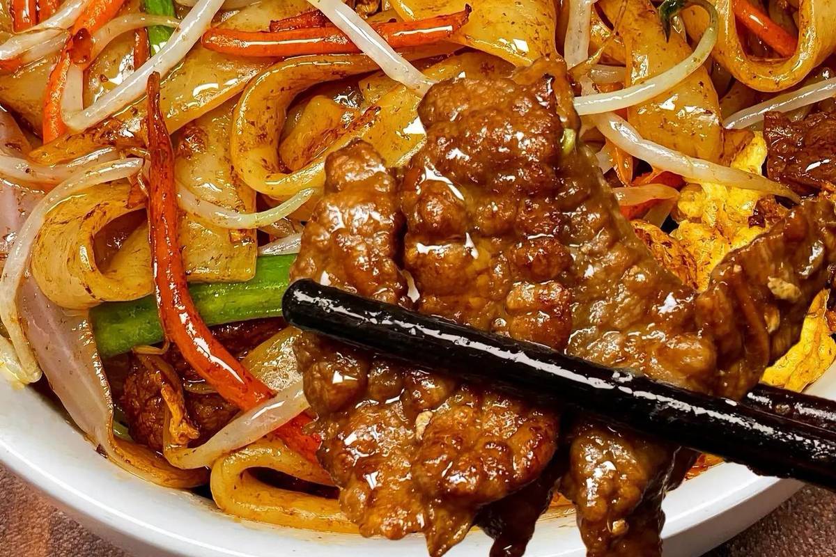Gan Chao Niu He close-up — glistening rice noodles with visible char marks and tender beef slices