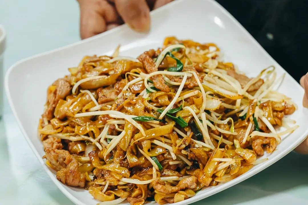 Gan Chao Niu He in a wok — the chef&rsquo;s toss captured mid-motion with steam and flame