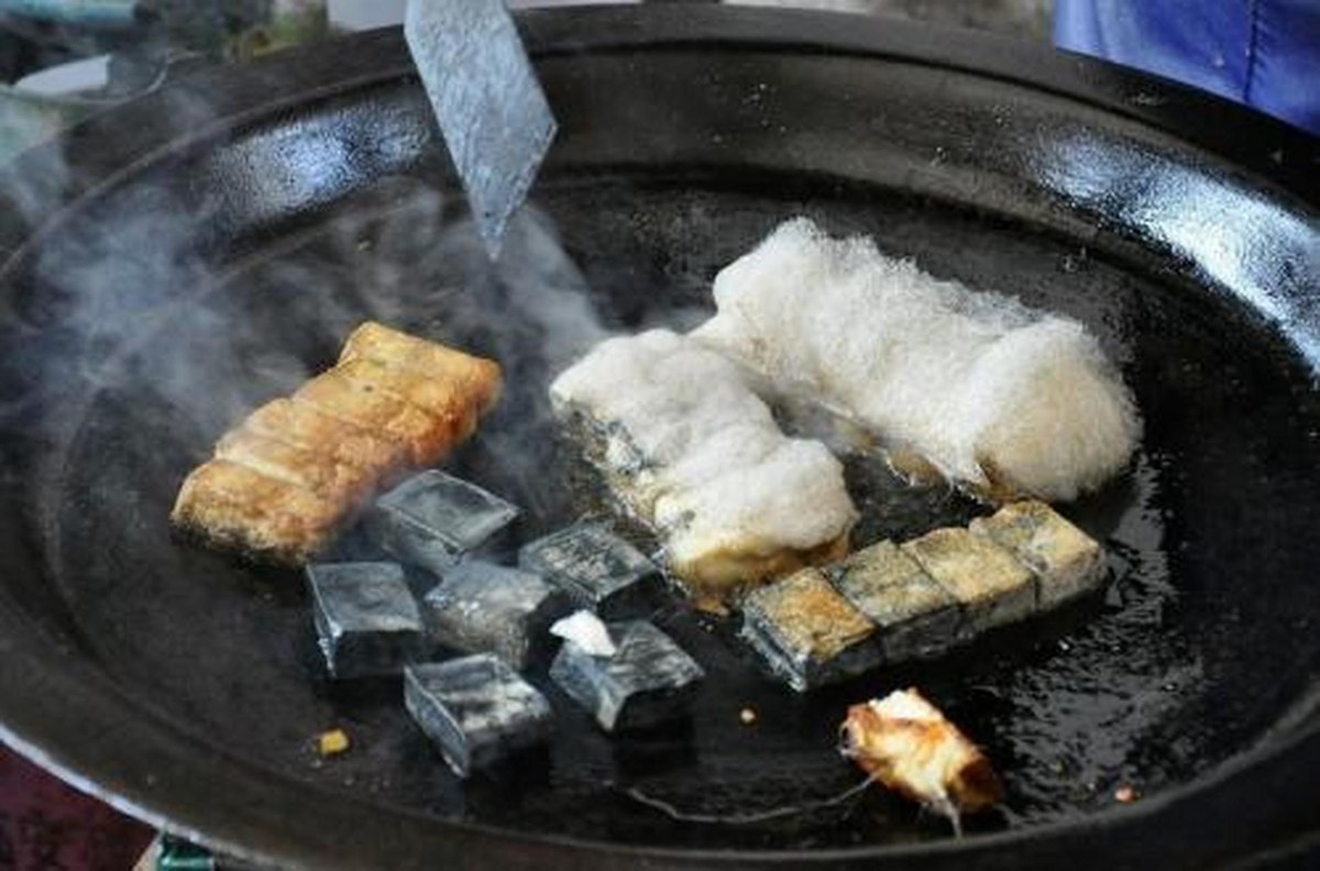 Hairy tofu — blocks of fermented tofu with their white mold fuzz searing in a wok, the fuzz collapsing into hot oil as they brown