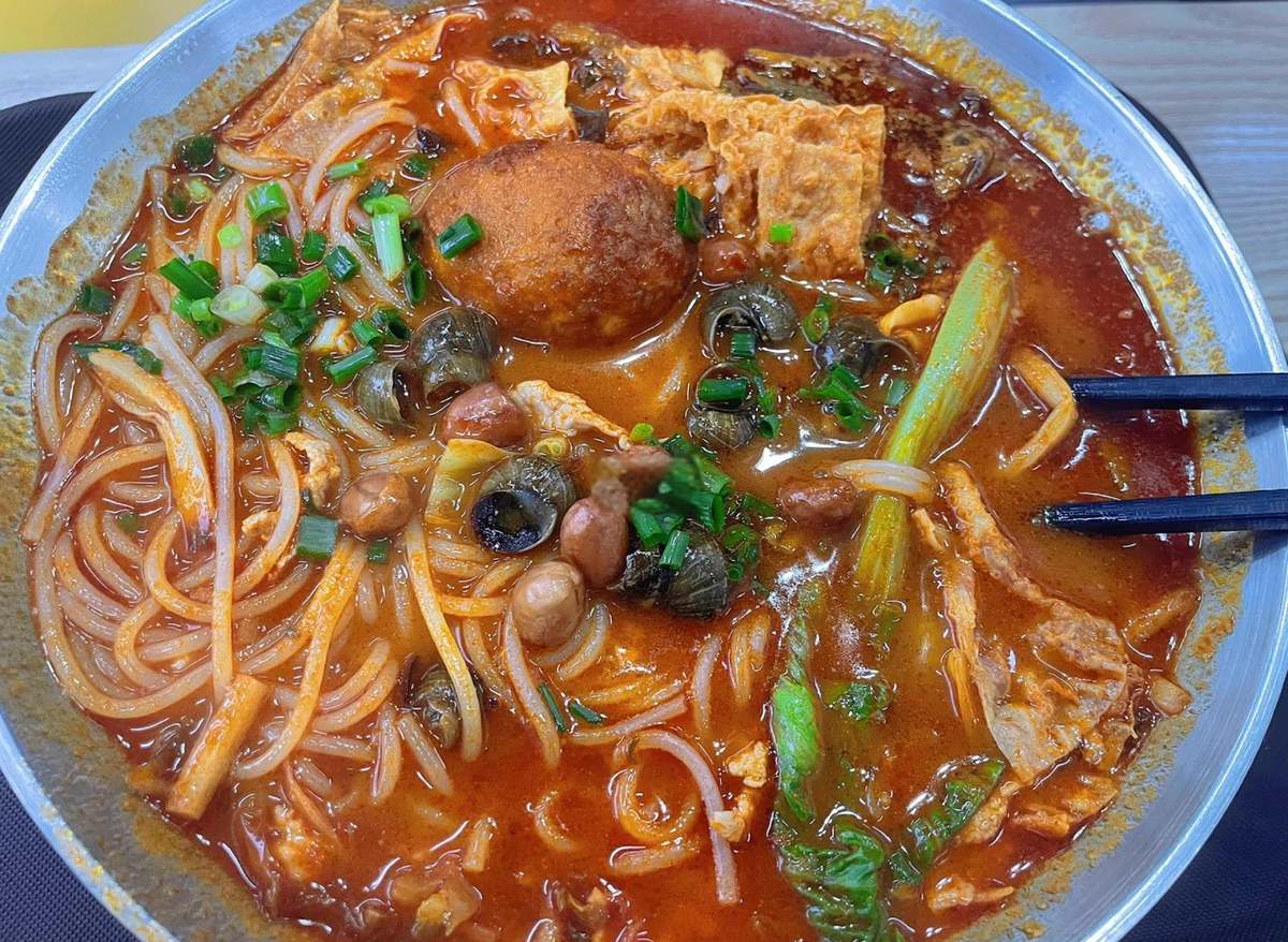 A bowl of luosifen just set down, chopsticks resting on the rim