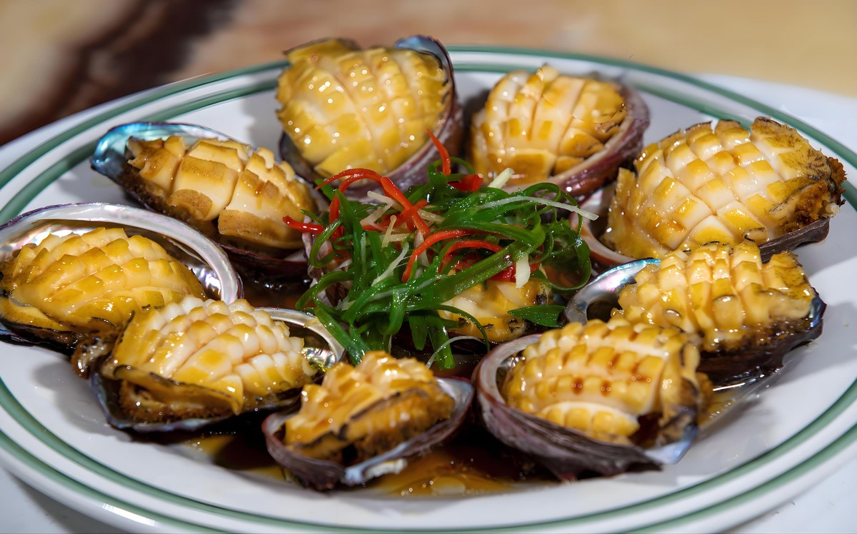 Braised abalone on the half shell, glossy with sauce — the expensive layer that goes on top of a poon choi