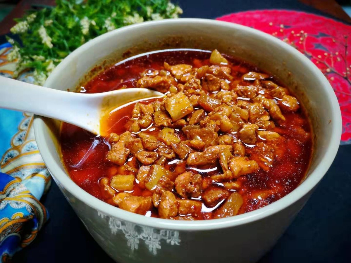 Saozi close-up — diced pork belly cooked down in vinegar and chili until the cubes turn amber, sitting in their own red oil