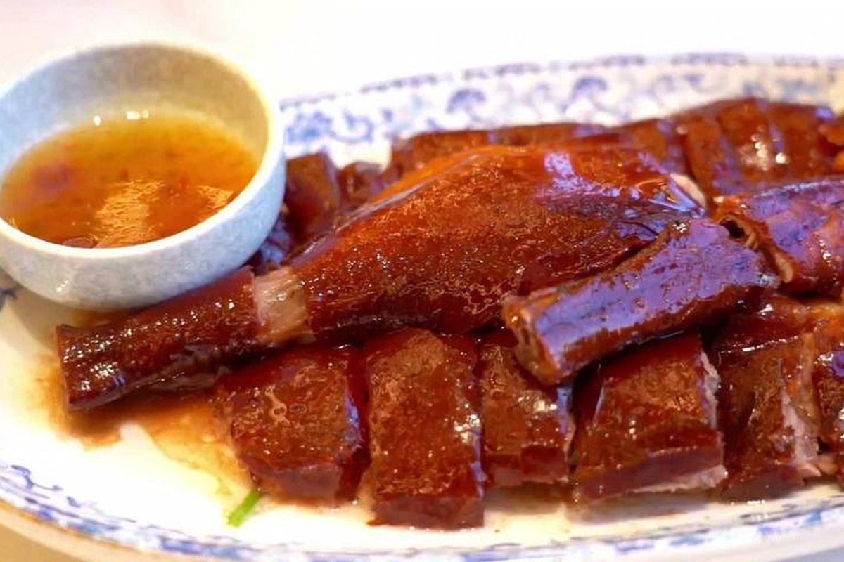 Roast goose chopped and plated — pieces arranged over the block with the plum sauce alongside