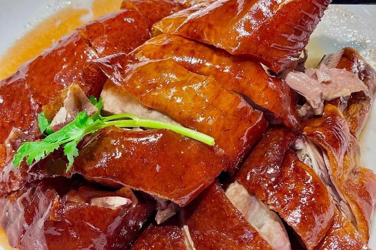 Roast goose close-up — the crisp amber skin and the layer of fat beneath it, chopped through to the bone