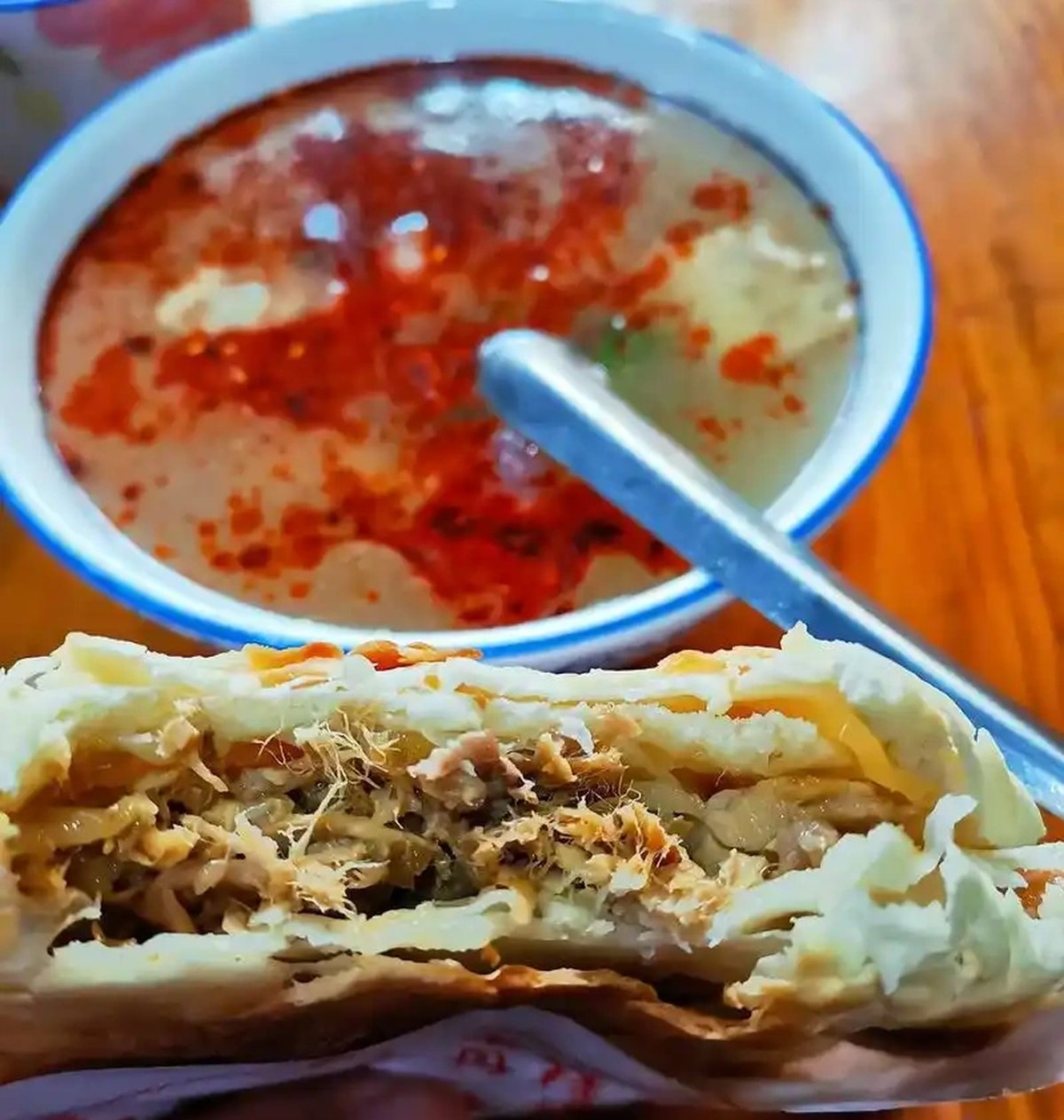 Rou Jia Mo on a plate — the finished sandwich with a side of chili oil