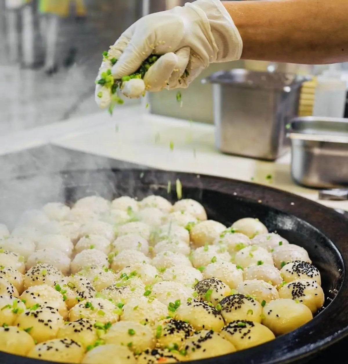Shengjianbao on a plate — a cluster of six golden-bottom buns served in a bamboo basket with black vinegar dip