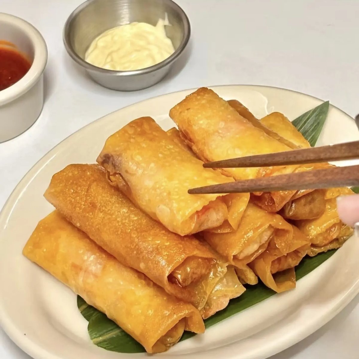 Spring rolls on a festive table — a platter surrounded by New Year decorations, dipping bowl of Worcestershire sauce, red tablecloth