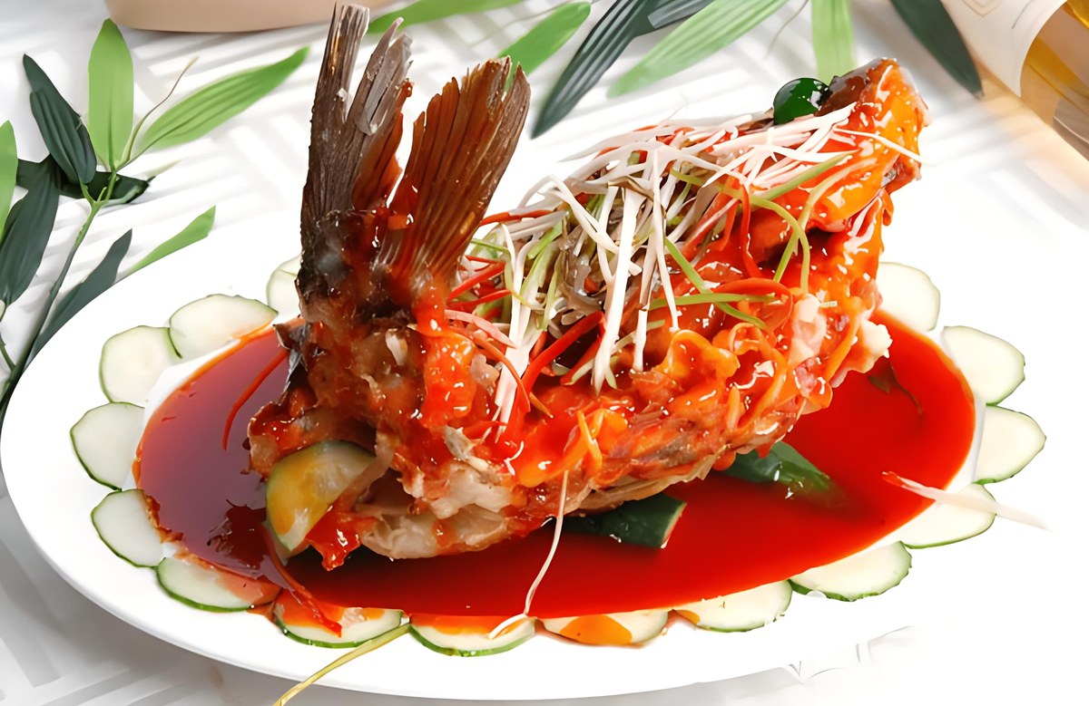 Sweet-and-sour carp — a whole fried carp, tail raised, its scored flesh fanned open under glossy vinegar sauce on a banquet platter