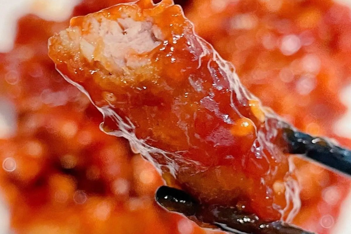 Sweet and Sour Pork — close-up of a single battered piece showing the crispy shell, glossy sauce, and tender pork interior