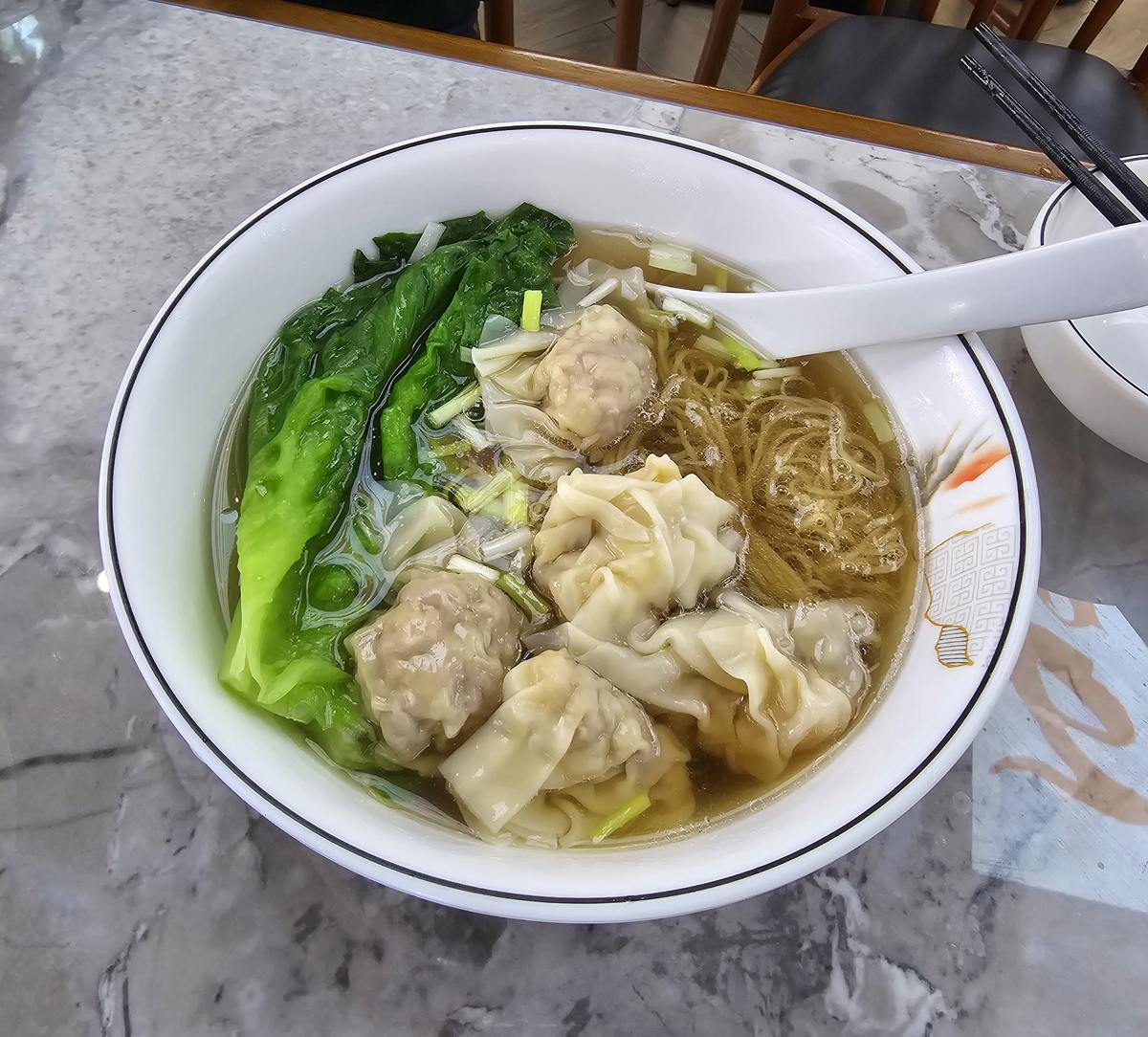 Wonton Noodles served at the table in a Hong Kong noodle shop, spoon still in the bowl