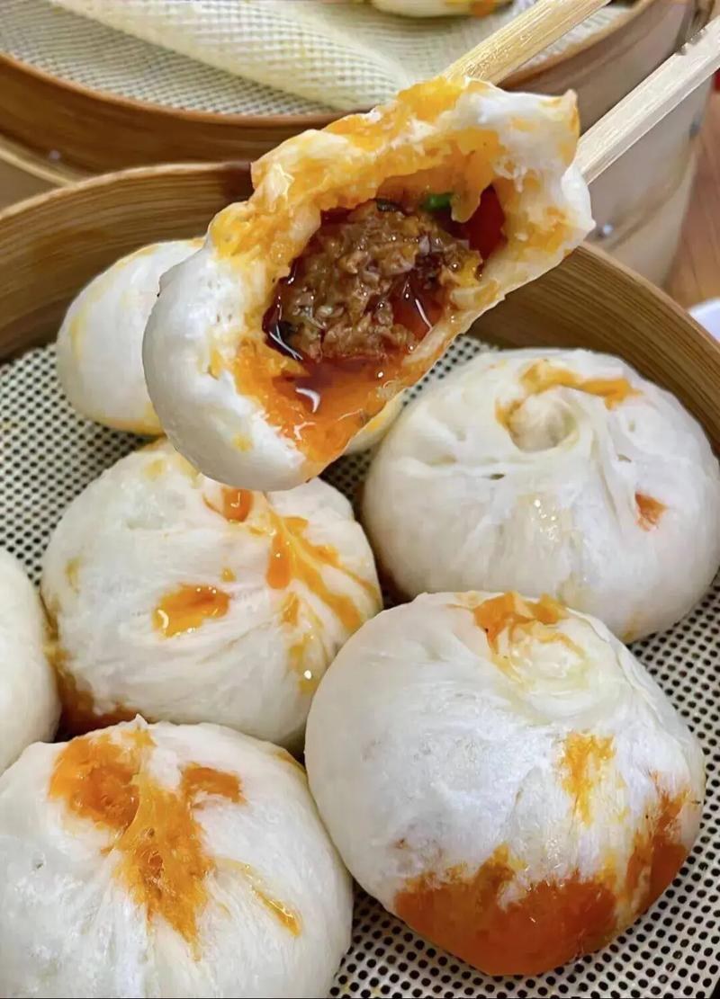 Xiao Long Bao close-up — translucent skin revealing the soup inside, chopsticks lifting one dumpling by its pleated crown