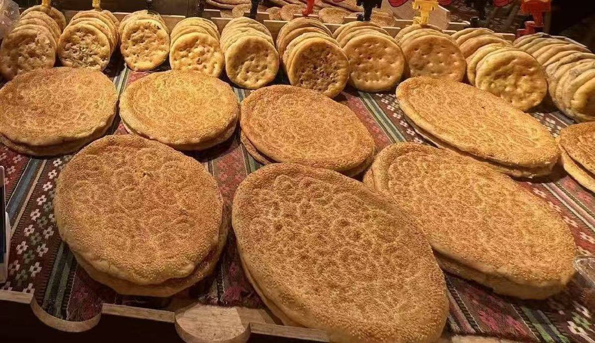 Rows of baked naan laid out on striped woven cloth at a Xinjiang market stall